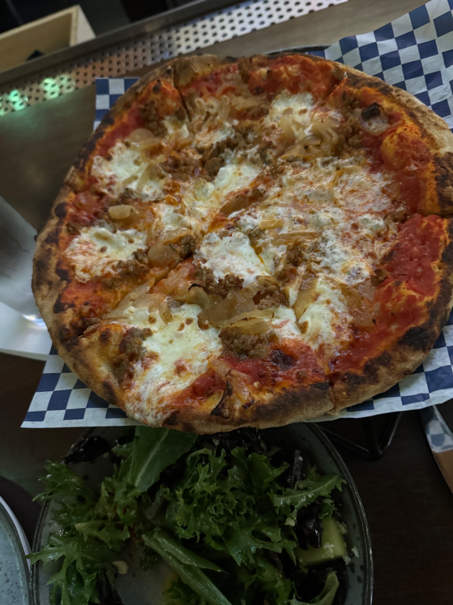 Wood-fired pizza with caramelized onions and side salad