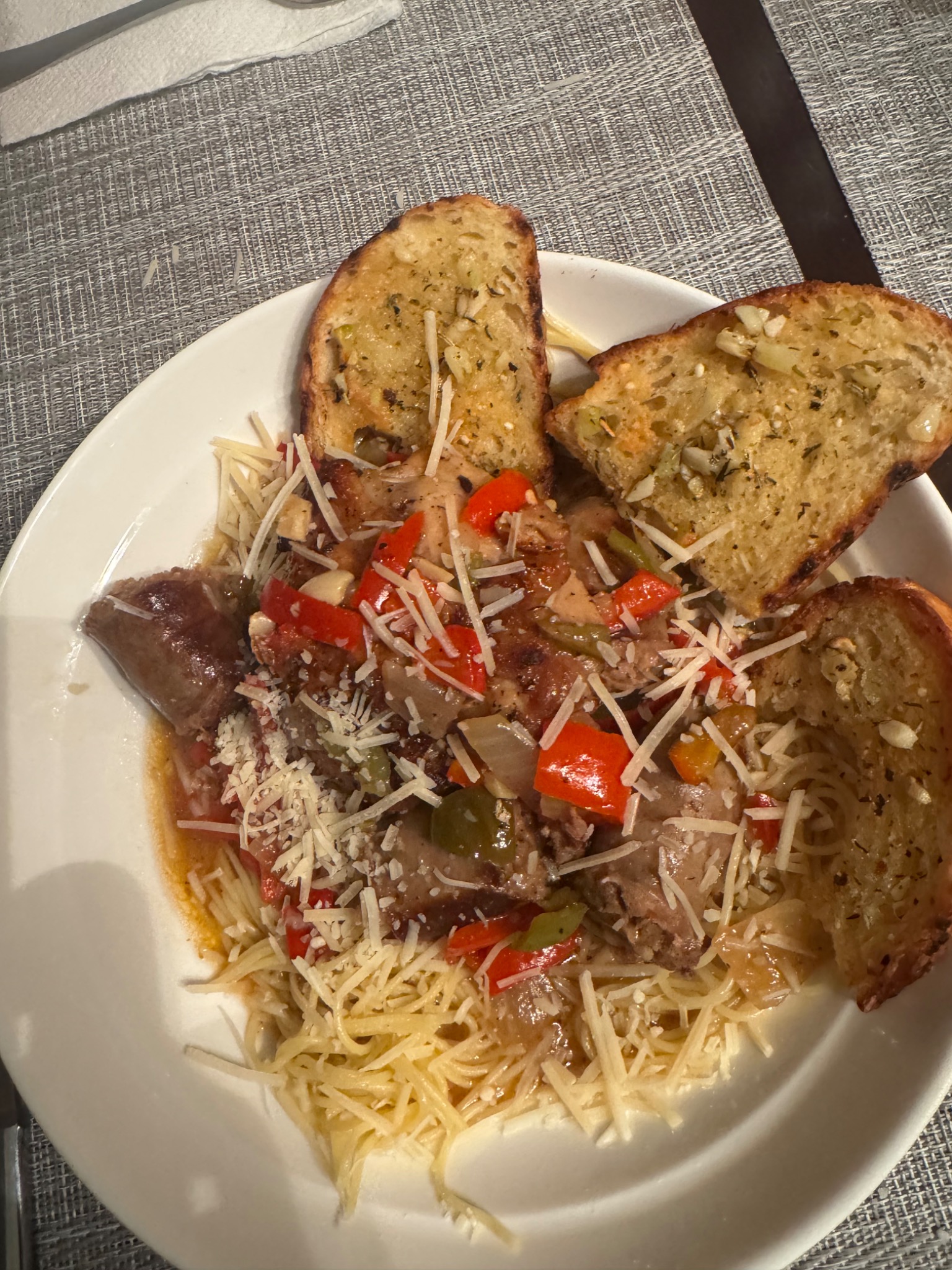 Sausage and peppers over pasta topped with parmesan